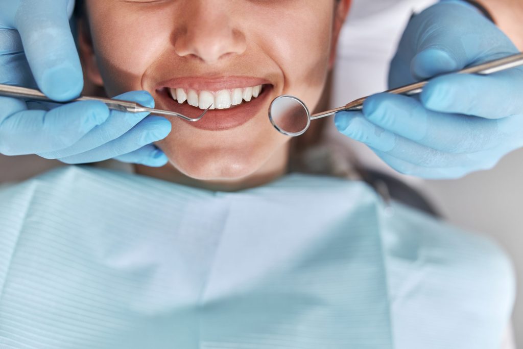 cheerful positive dentist client dentistry female patient dental procedure doctor using dental instruments modern dental clinic close up